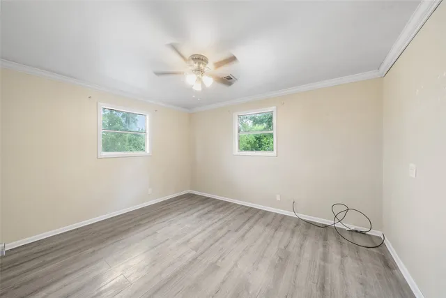 a view of an empty room with a window and wooden floor