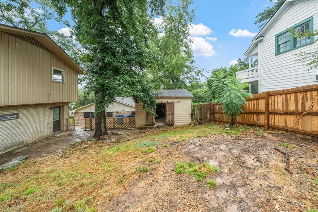 a backyard of a house with large trees and table and chairs