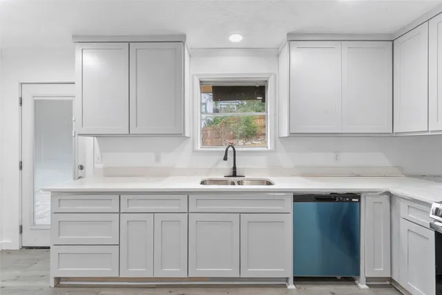 a kitchen with white cabinets and sink
