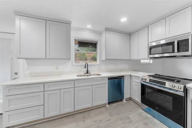 a kitchen with white cabinets stainless steel appliances and sink