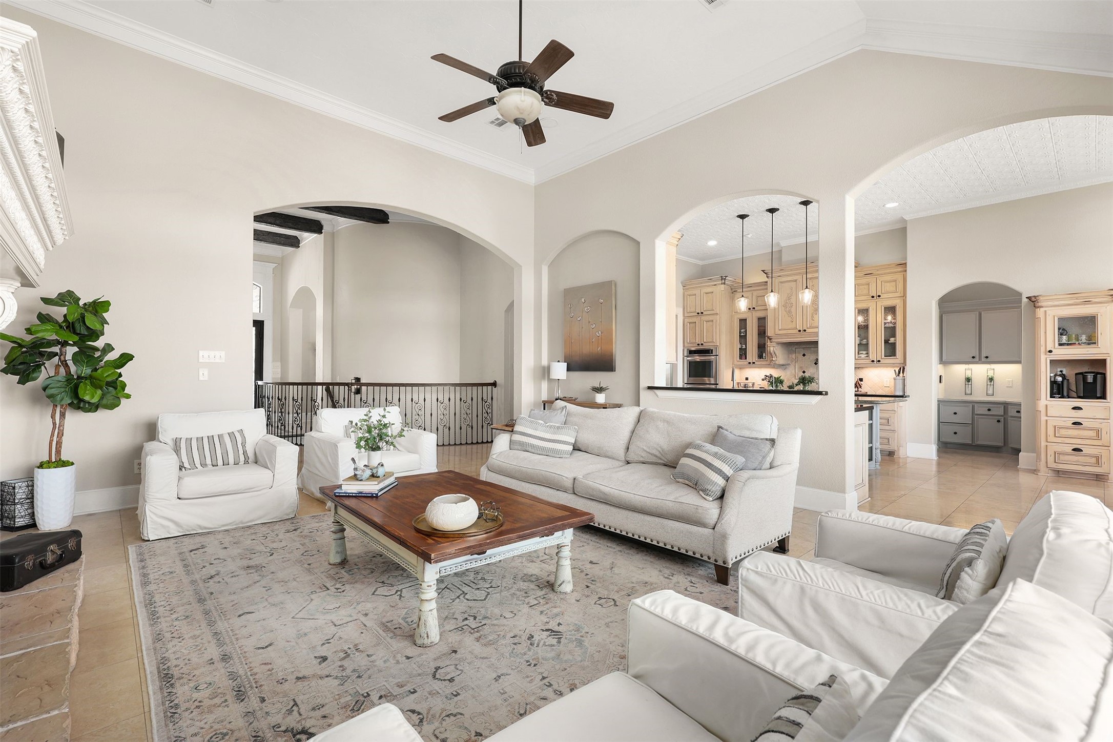 10896 Decatur Street Willis, TX 77318 - Photo 26 of 50 This spacious living room boasts high ceilings, neutral tones, and elegant archways leading to an open kitchen, offering comfortable seating, a ceiling fan, and stylish light fixtures for a warm, inviting atmosphere.