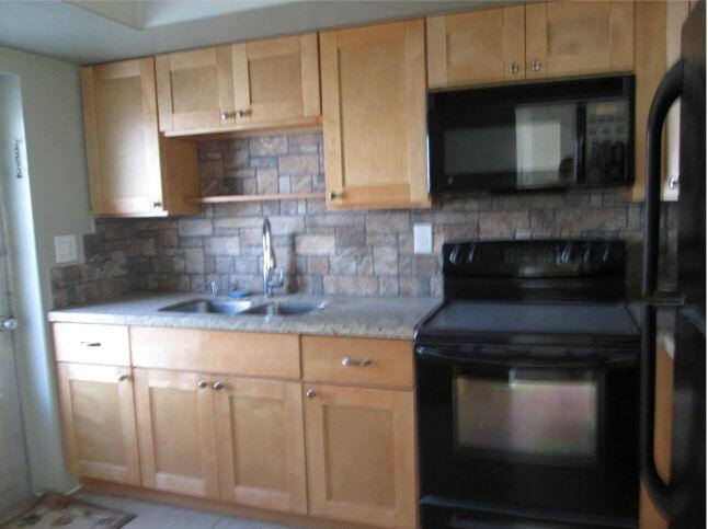 1911 Northeast 27th Court, Unit 13 Lighthouse Point, FL 33064 - Photo 39 of 61 a kitchen with granite countertop white cabinets and black appliances