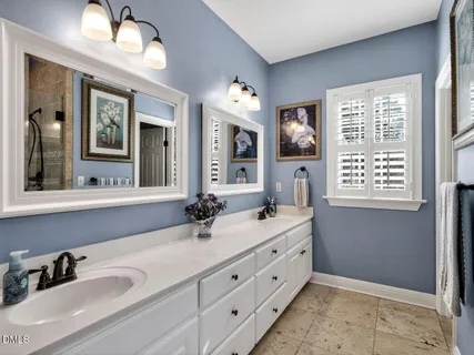 a bathroom with double vanity sink a two mirror a window a bathtub and vanity