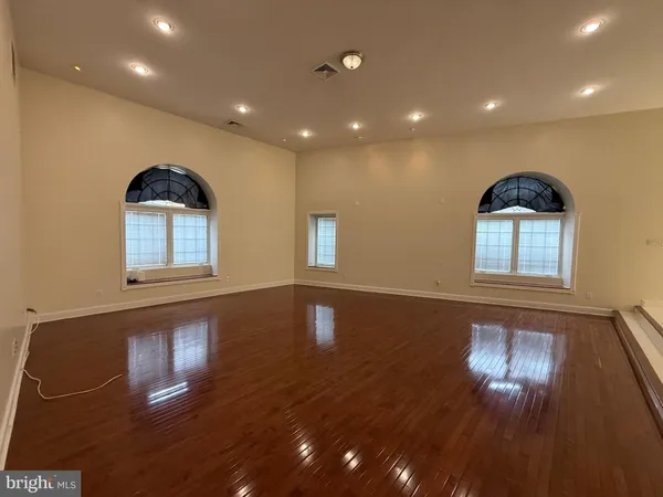 a view of empty room with wooden floor and windows