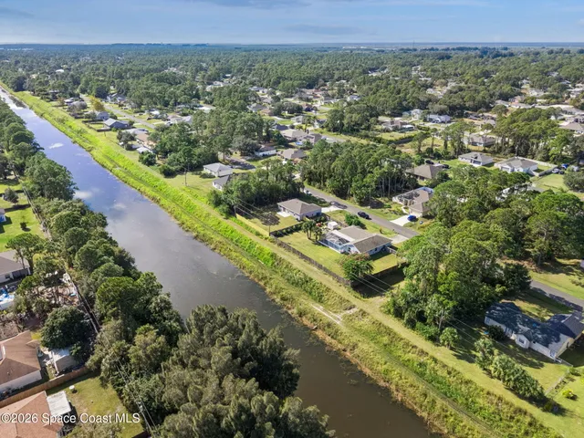 an aerial view of residential houses with outdoor space and trees
