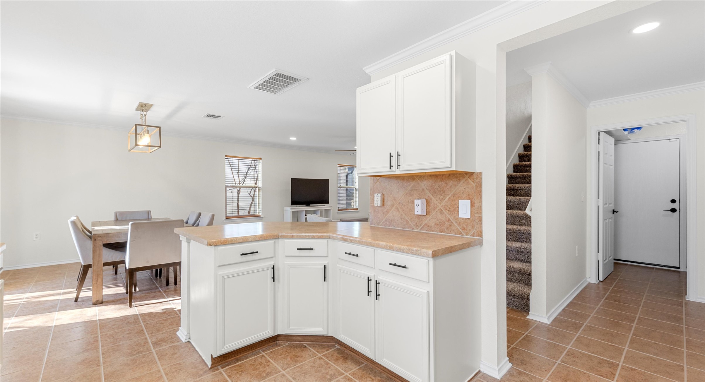 8613 Wiley Way Austin, TX 78747 - Photo 12 of 33 Kitchen featuring white cabinets, light countertops, a peninsula, light tile patterned floors, and decorative backsplash