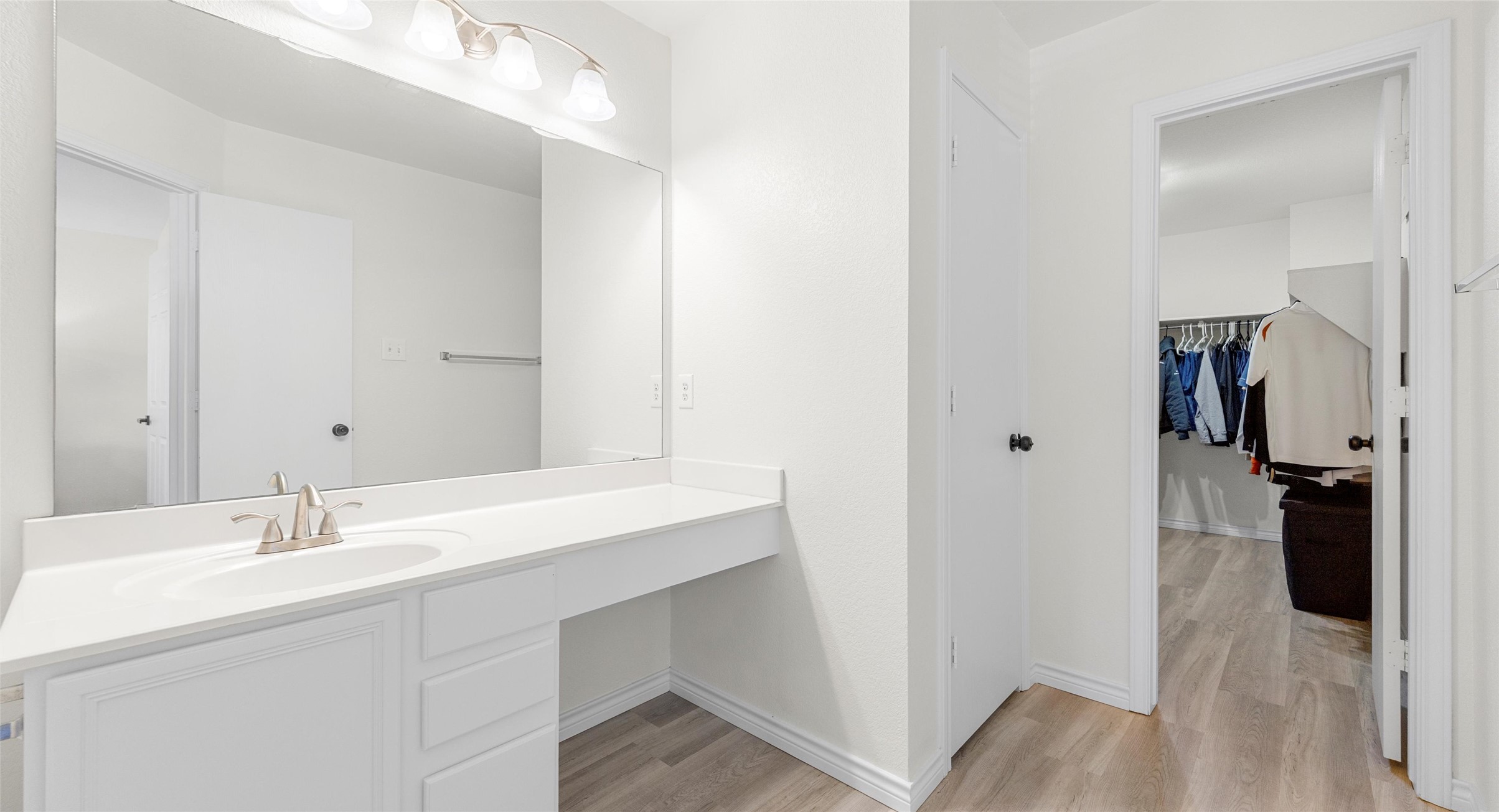 8613 Wiley Way Austin, TX 78747 - Photo 21 of 33 Bathroom featuring vanity, light wood-style floors, and a walk in closet
