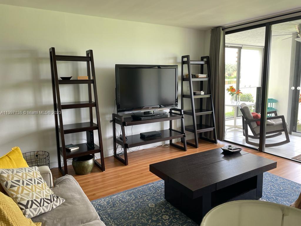 a living room with furniture a flat screen tv and a floor to ceiling window