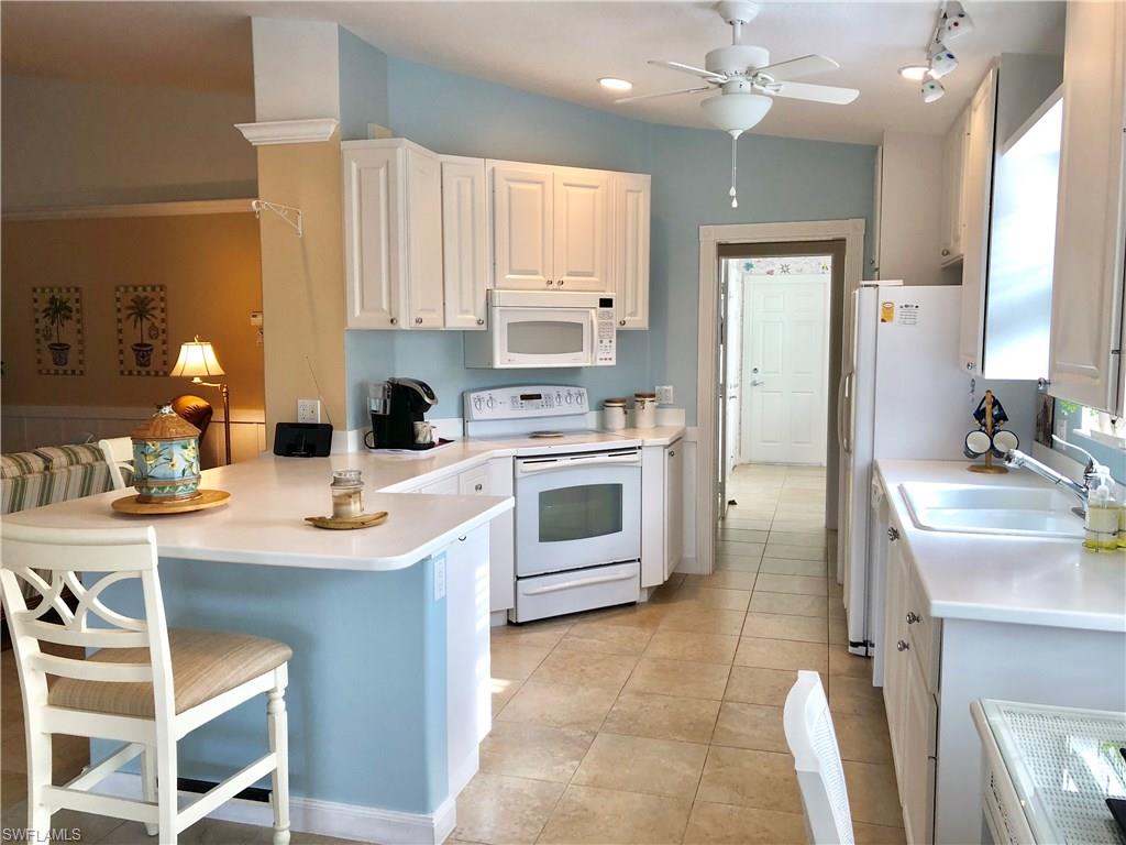 7640 Rozzini Lane Naples, FL 34114 - Photo 6 of 17 a kitchen with stainless steel appliances a sink a stove a refrigerator cabinets and chairs