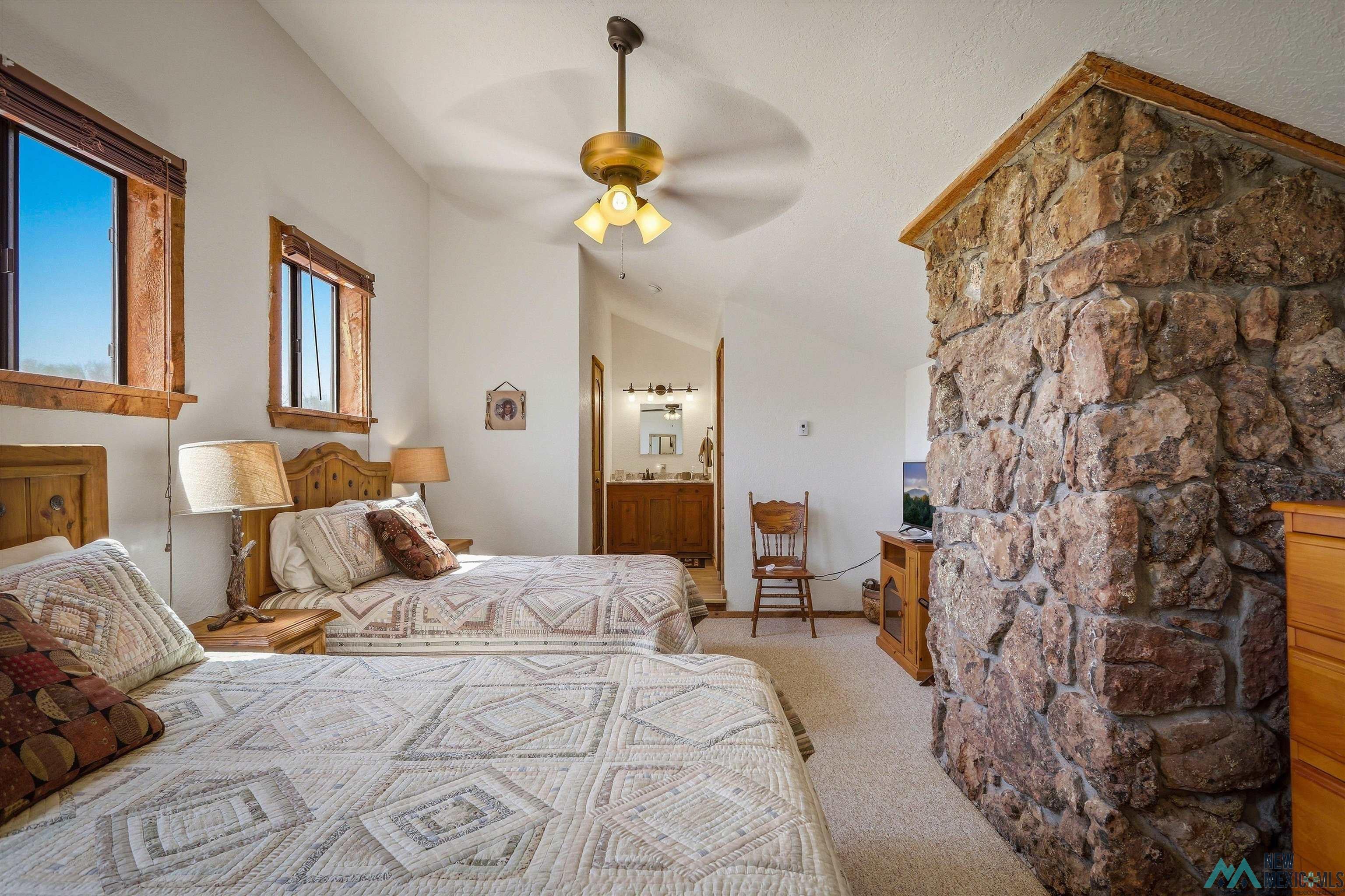 83 Juniper Road Chama, NM 87520 - Photo 40 of 56 Room featuring a stone-clad architectural element, vaulted ceiling, and light-toned carpet flooring