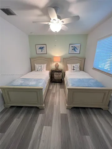 a bedroom with a bed wooden floor and a ceiling fan