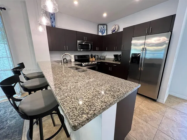 a kitchen with stainless steel appliances granite countertop a sink refrigerator and microwave