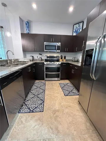 a kitchen with stainless steel appliances granite countertop a stove a sink and a refrigerator