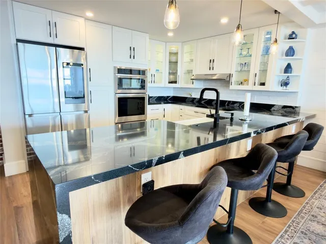 a kitchen with stainless steel appliances granite countertop a sink a stove and a refrigerator