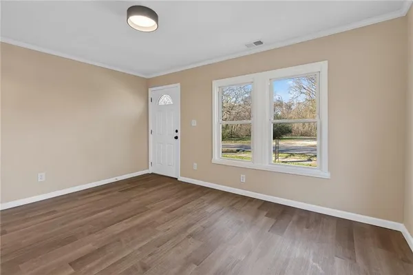 an empty room with wooden floor and windows