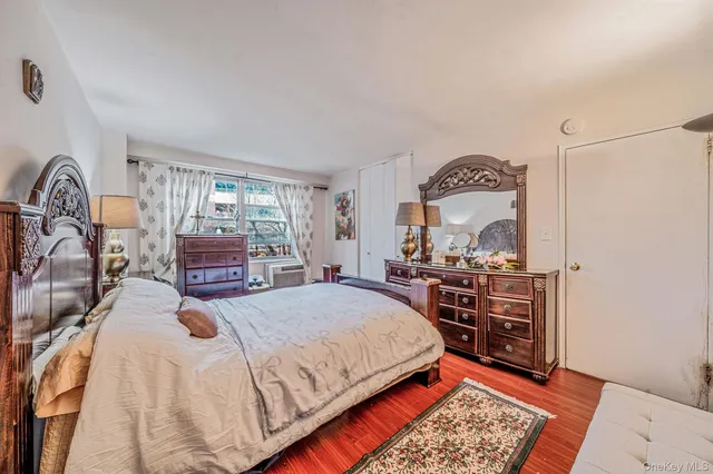 a bedroom with a bed a dresser next to a window