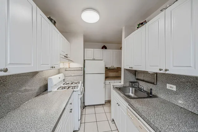 a kitchen with granite countertop a sink a stove and a refrigerator