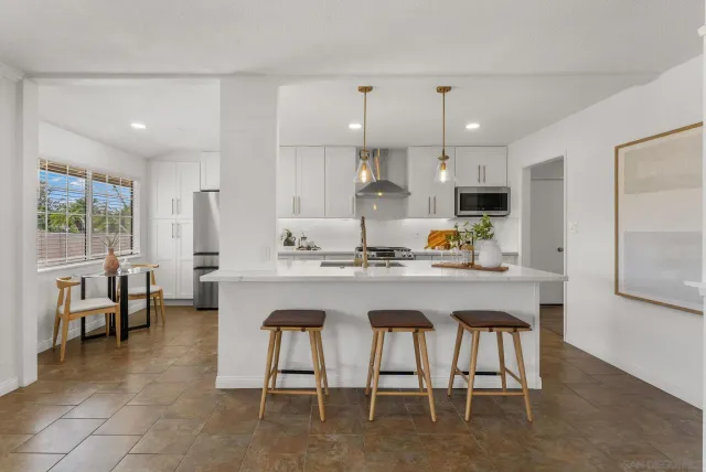 a kitchen with stainless steel appliances granite countertop a table chairs sink refrigerator and microwave