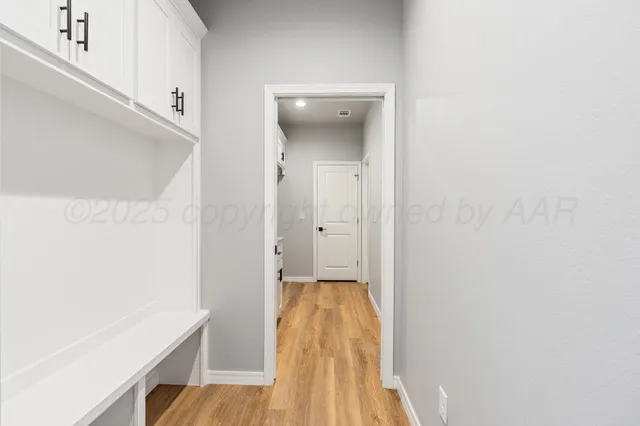 a view of a hallway with wooden floor and a bathroom