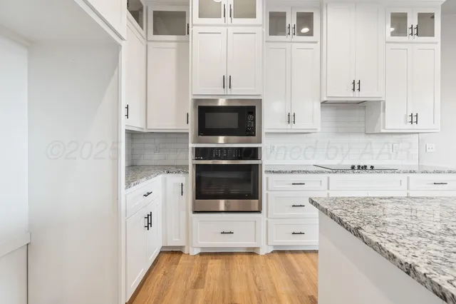 a kitchen with stainless steel appliances granite countertop a stove and white cabinets