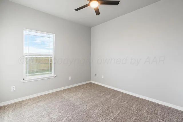 an empty room with a chandelier fan and windows