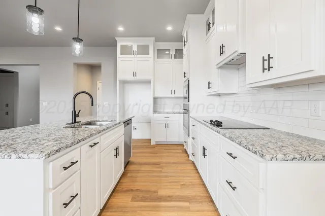 a large kitchen with stainless steel appliances kitchen island a large counter top a sink and a refrigerator