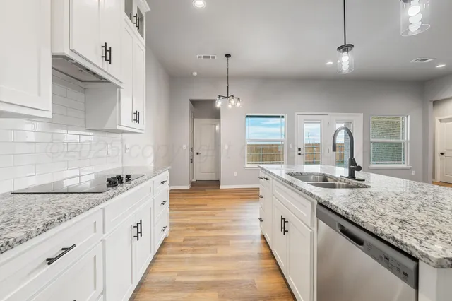 a large kitchen with a granite countertop sink and white cabinets