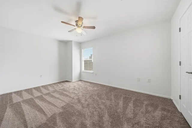 an empty room with a window and a fan