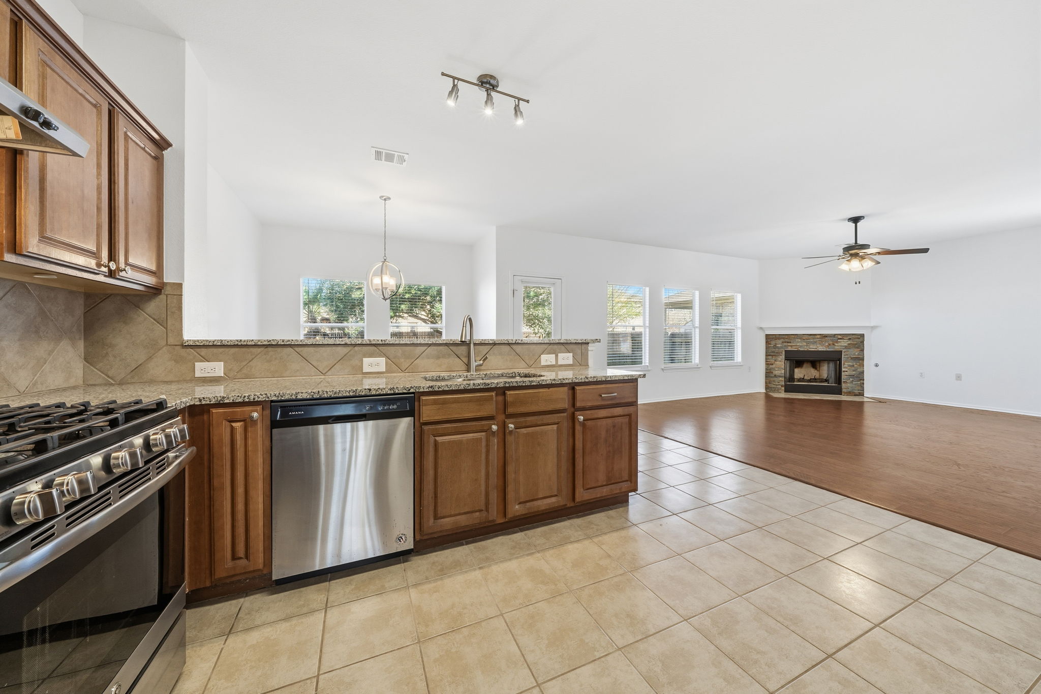 5712 Zachary Scott Street Austin, TX 78747 - Photo 7 of 28 Kitchen with appliances with stainless steel finishes, brown cabinets, a fireplace, and plenty of natural light