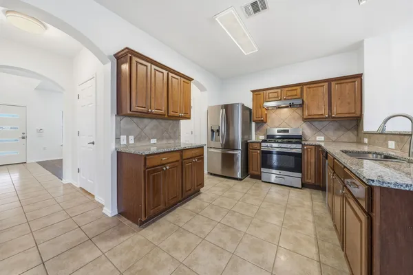 a kitchen with stainless steel appliances granite countertop a stove a sink and a refrigerator