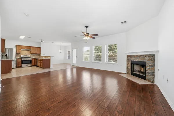 an empty room with wooden floor fireplace and windows