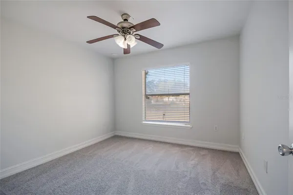 an empty room with a chandelier fan and closet area