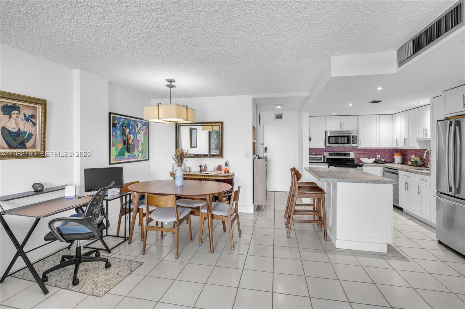 150 Southeast 25th Road, Unit 8H Miami, FL 33129 - Photo 35 of 41 a kitchen with stainless steel appliances kitchen island granite countertop a table chairs and a refrigerator