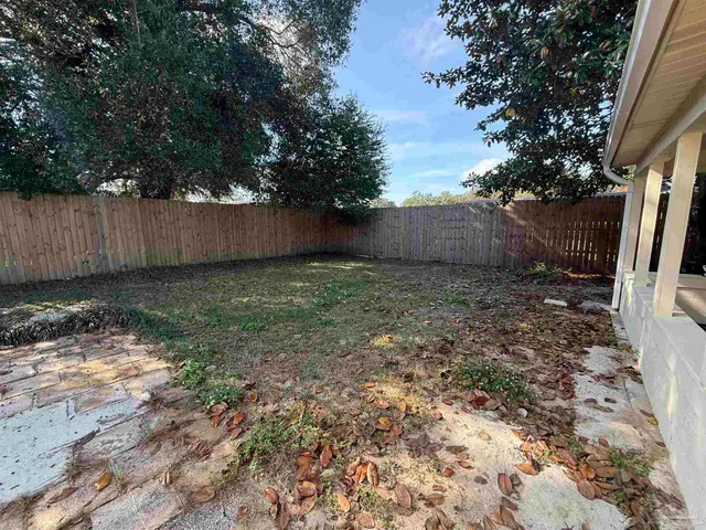 a view of a backyard with trees and wooden fence