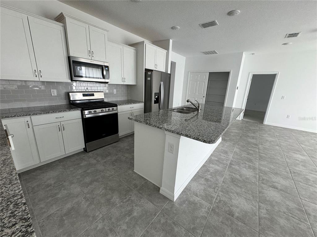 6425 Southwest 78th Ave Road Ocala, FL 34474 - Photo 5 of 13 a kitchen with stainless steel appliances granite countertop a stove a sink and a refrigerator