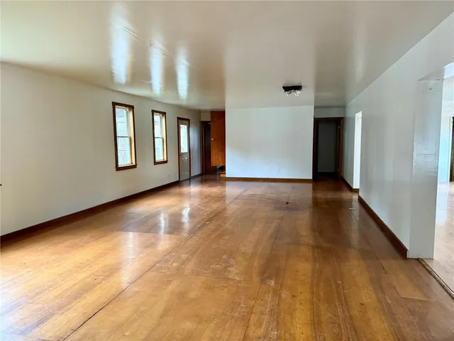 a view of an empty room with window and wooden floor