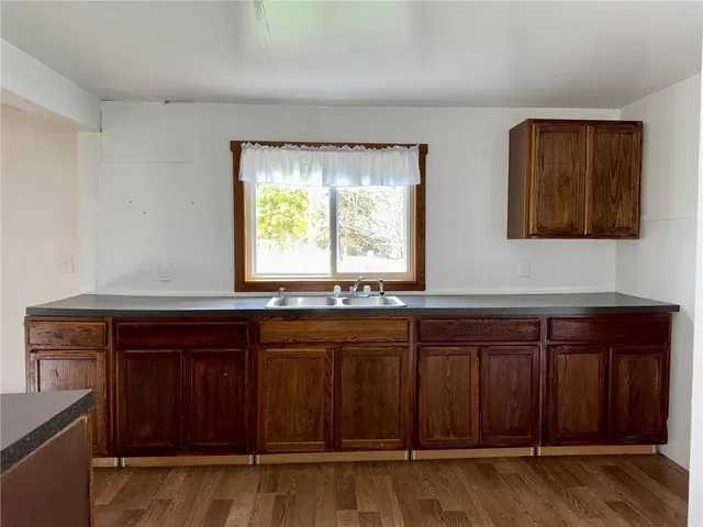 a kitchen with granite countertop a sink cabinets and wooden floor