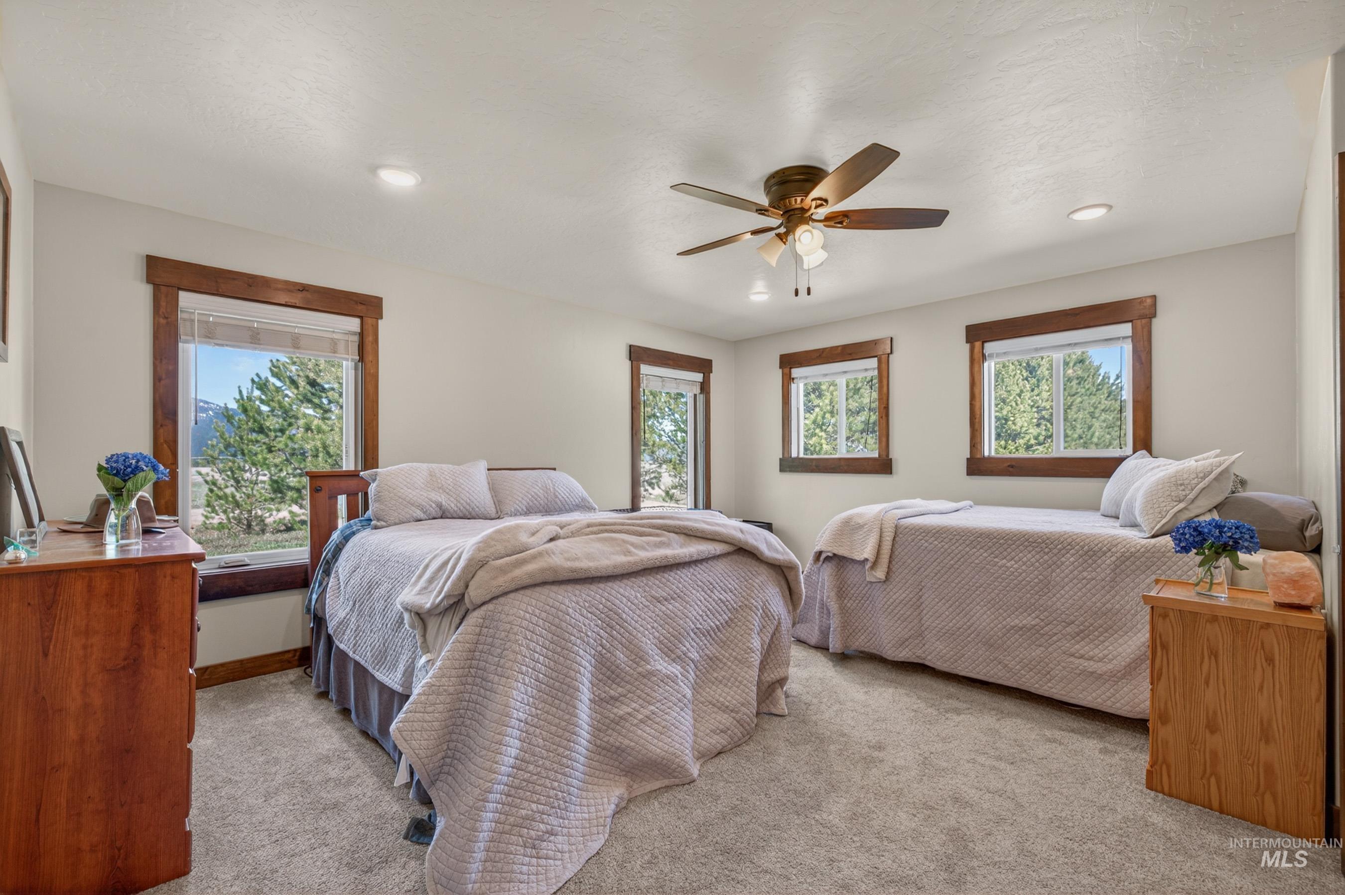 13388 Norwood Road McCall, ID 83638 - Photo 24 of 44 Bedroom featuring light gray carpet, multiple windows with wood trim, recessed lighting, and a ceiling fan