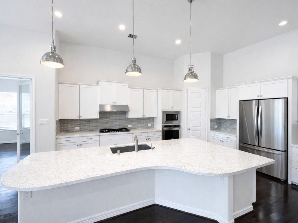 10407 Roseate Skimmer Conroe, TX 77385 - Photo 11 of 30 a kitchen with stainless steel appliances kitchen island a refrigerator a sink dishwasher a oven a stove and white cabinets with wooden floor