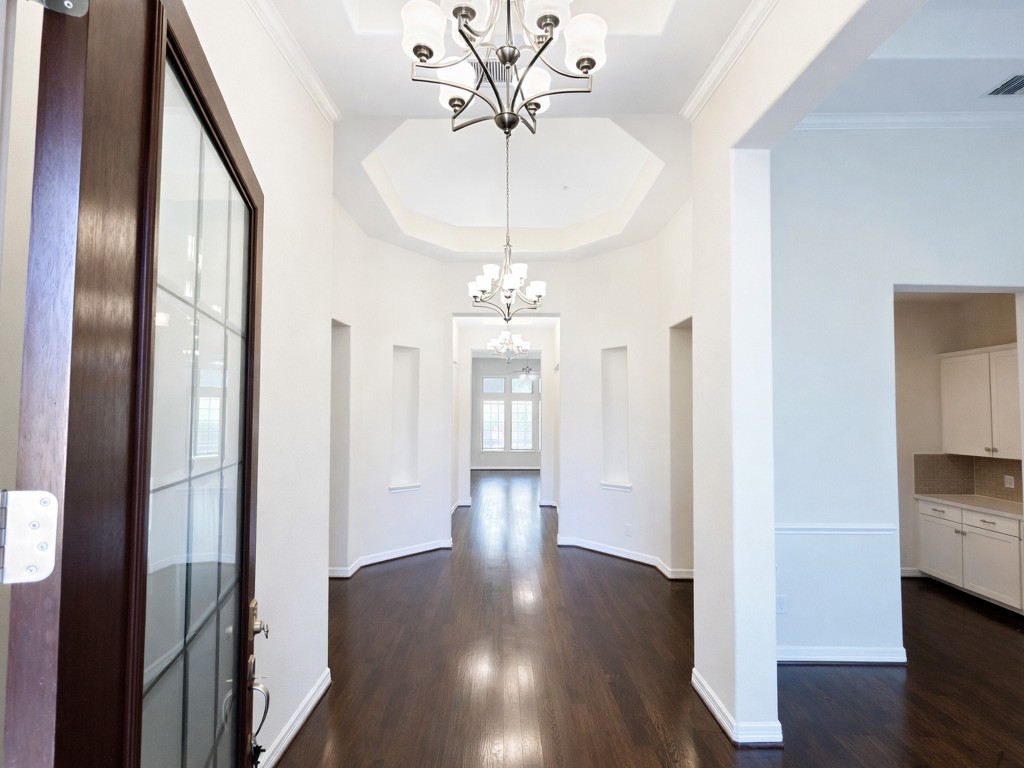 10407 Roseate Skimmer Conroe, TX 77385 - Photo 3 of 30 a view of a hallway with wooden floor and a chandelier