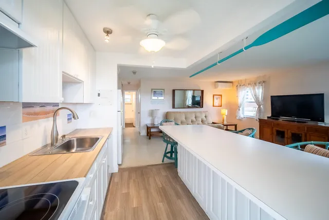 a view of a kitchen with kitchen island a sink wooden floor and living room view