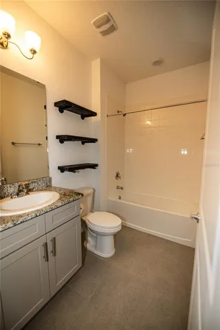 a bathroom with a granite countertop toilet a sink and a bathtub