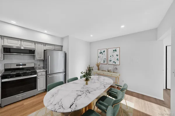 a kitchen with stainless steel appliances a dining table chairs refrigerator and stove