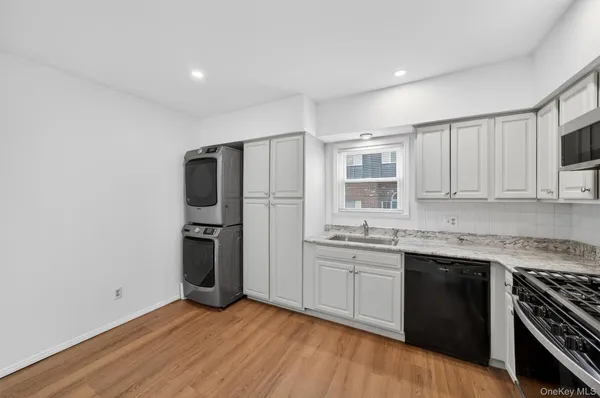 a kitchen with stainless steel appliances granite countertop a stove a sink dishwasher a refrigerator and a microwave oven with wooden floor