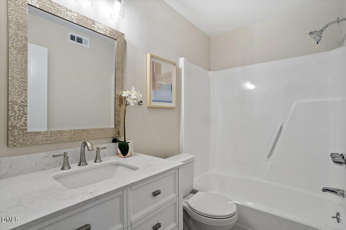 3306 Prudence Street Durham, NC 27704 - Photo 16 of 22 a bathroom with a granite countertop sink toilet a mirror and shower