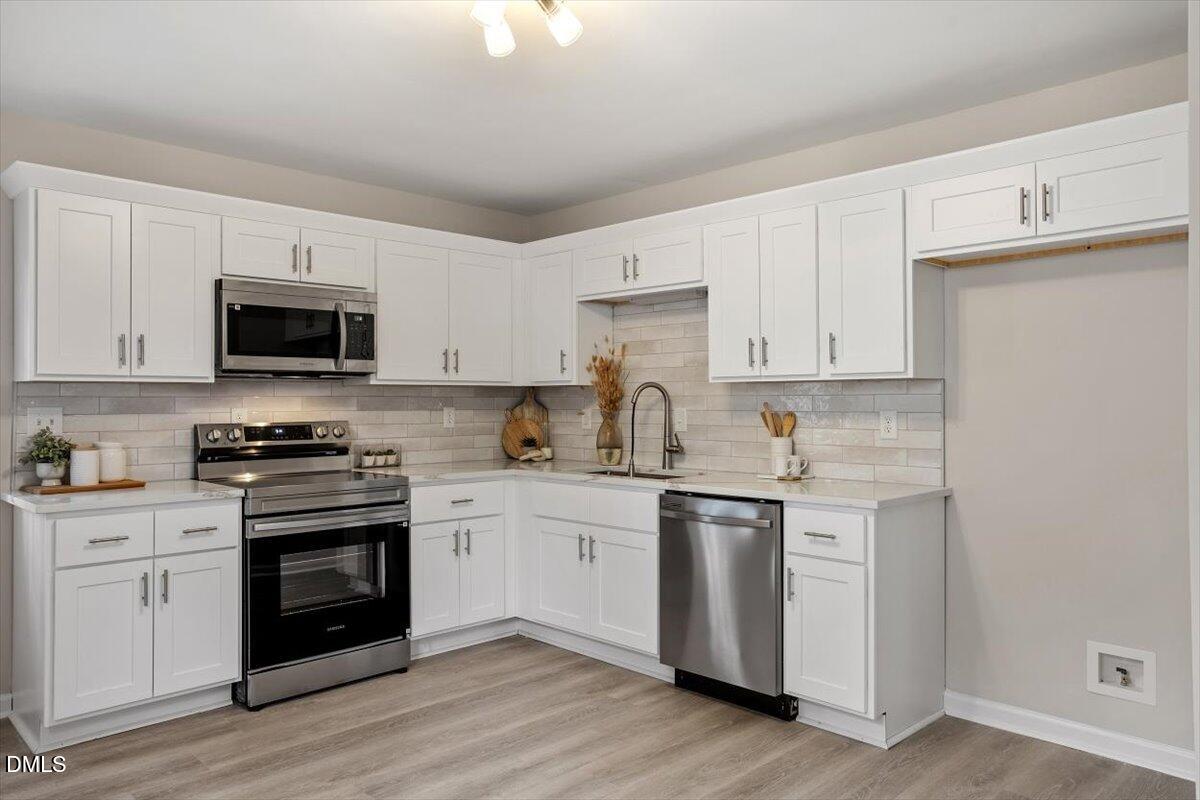3306 Prudence Street Durham, NC 27704 - Photo 6 of 22 a kitchen with stainless steel appliances granite countertop white cabinets a sink a stove a microwave and wooden floors