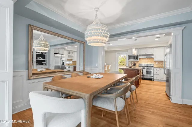 a view of a dining room with furniture a chandelier and wooden floor