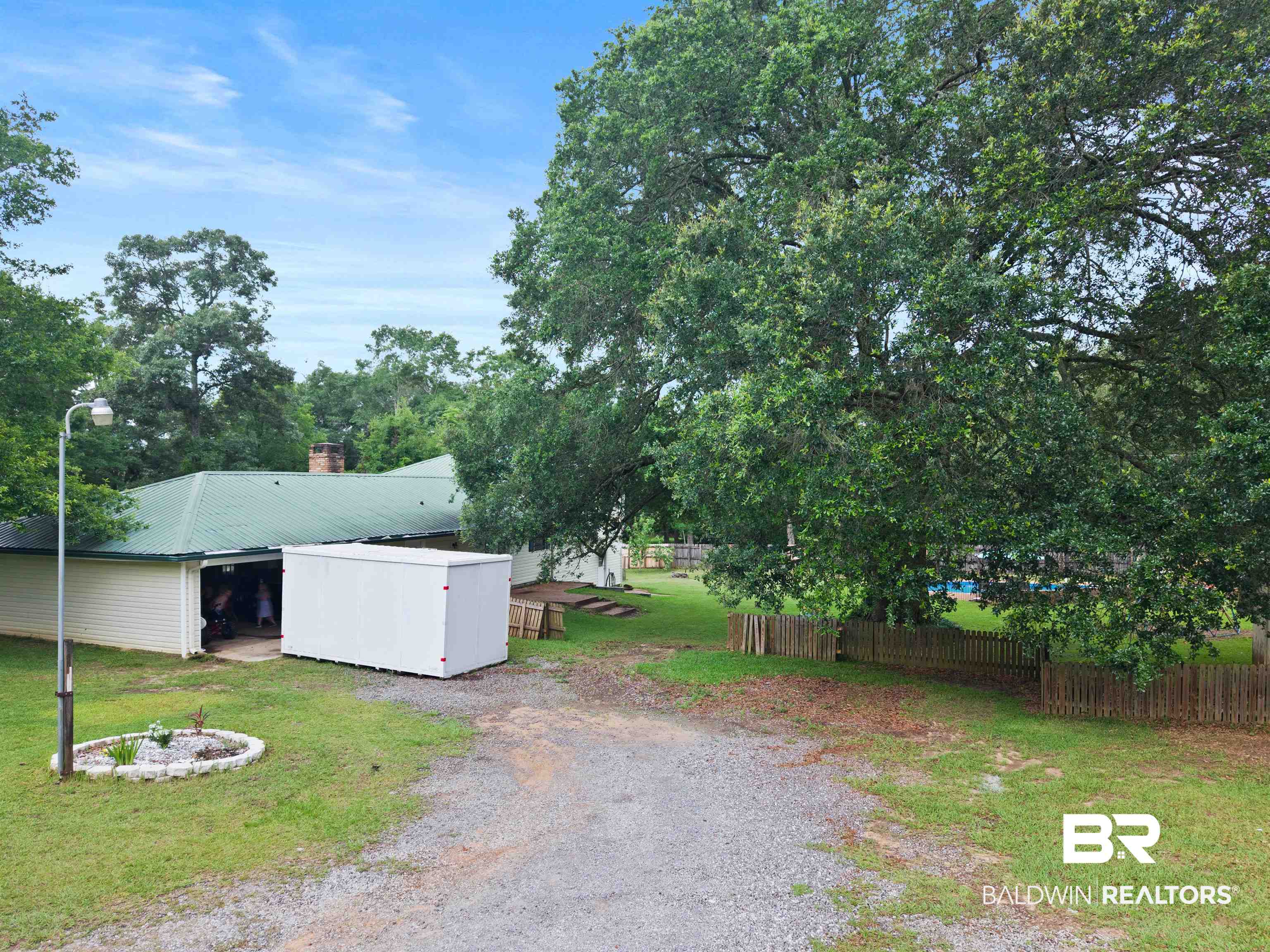 10420 Johnson Road South Mobile, AL 36695 - Photo 52 of 75 Expansive gravel driveway leading to a residence featuring a green metal roof and white siding