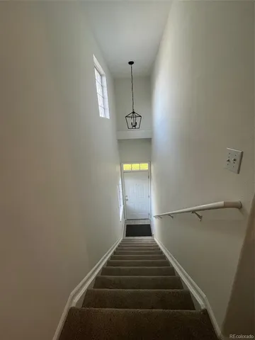 a view of a hallway with stairs and wooden floor