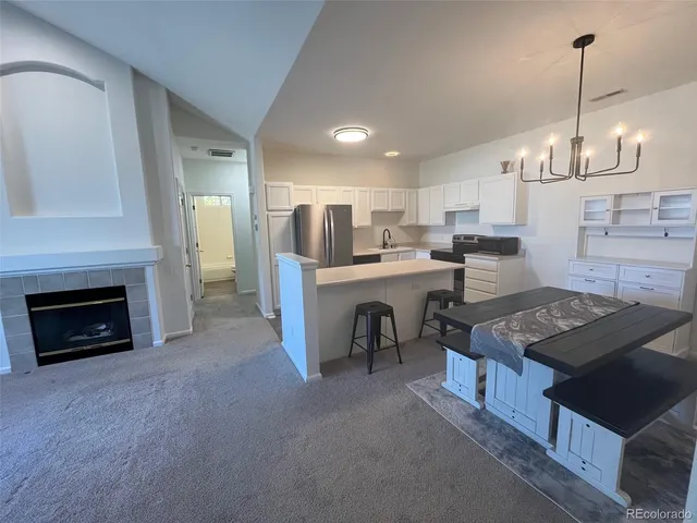 a open kitchen with stainless steel appliances granite countertop a stove top oven a sink dishwasher a dining table and chairs with wooden floor